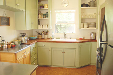 This is an example of an eclectic separate kitchen in Portland with green cabinets, a drop-in sink, open cabinets, wood benchtops and stainless steel appliances.