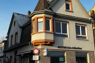 Geräumiges, Dreistöckiges Mediterranes Haus mit grauer Fassadenfarbe, Satteldach, Schindeldach, schwarzem Dach, Schindeln und Dachgaube in Sonstige