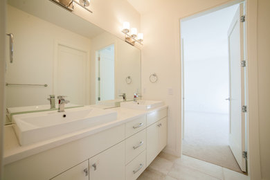 Bathroom - mid-sized contemporary beige tile ceramic tile bathroom idea in Vancouver with a vessel sink, flat-panel cabinets, white cabinets, quartz countertops, a one-piece toilet and white walls