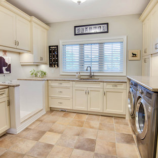 Ejemplo de lavadero multiusos y en U, tradicional, grande, con fregadero bajoencimera, armarios estilo shaker, puertas de armario blancas, encimera de granito, paredes blancas, suelo de baldosas de porcelana, lavadora y secadora juntas y suelo beige