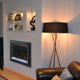 Bild på ett mellanstort funkis separat vardagsrum, med ett finrum, lila väggar, mellanmörkt trägolv, en hängande öppen spis, en spiselkrans i metall och en fristående TV