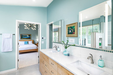 Example of a large trendy master white tile and ceramic tile gray floor, double-sink, ceramic tile and vaulted ceiling bathroom design with blue walls, white countertops, a built-in vanity, flat-panel cabinets, light wood cabinets, a bidet, an undermount sink, quartz countertops, a hinged shower door and a niche