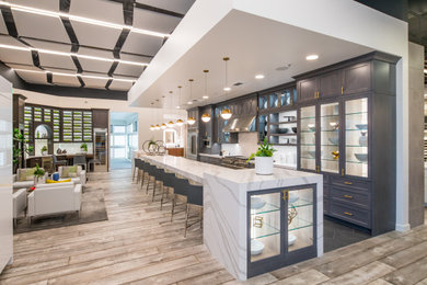 Example of a large transitional galley porcelain tile and gray floor eat-in kitchen design in San Francisco with shaker cabinets, gray cabinets, quartz countertops, white backsplash, ceramic backsplash, stainless steel appliances, an island and white countertops