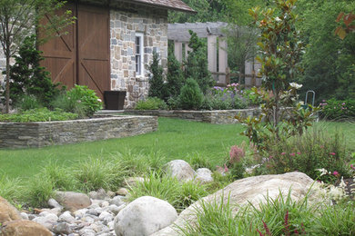 This is an example of an expansive traditional backyard partial sun garden in New York with natural stone pavers.