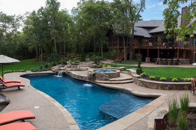 Design ideas for a large arts and crafts backyard custom-shaped pool in Kansas City with a water feature and concrete slab.