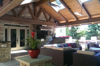 Inspiration for a large craftsman backyard stone patio kitchen remodel in Seattle with a pergola