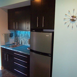 シンシナティの小さいモダンスタイルのおしゃれなウェットバー (ドロップインシンク、フラットパネル扉のキャビネット、黒いキャビネット、タイルカウンター、青いキッチンパネル、ガラスタイルのキッチンパネル) の写真