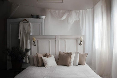 Diseño de habitación de invitados romántica pequeña sin chimenea con paredes blancas, suelo laminado, suelo gris y vigas vistas