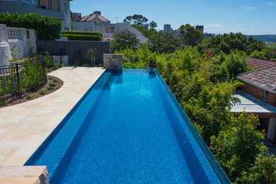 This is an example of a large mediterranean backyard rectangular lap pool in Sydney with natural stone pavers.