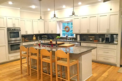 Example of a large trendy l-shaped light wood floor open concept kitchen design in Atlanta with a double-bowl sink, shaker cabinets, white cabinets, granite countertops, gray backsplash, stainless steel appliances and an island
