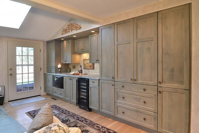 Home bar - large country single-wall light wood floor home bar idea in Boston with a drop-in sink, recessed-panel cabinets, granite countertops and gray backsplash
