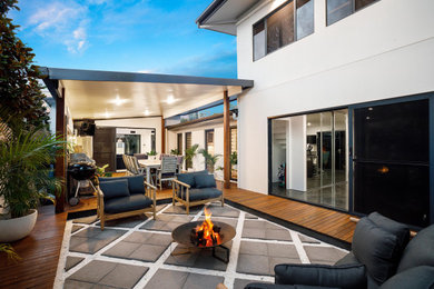 This is an example of a mid-sized contemporary backyard and ground level deck in Gold Coast - Tweed with an outdoor kitchen and a pergola.