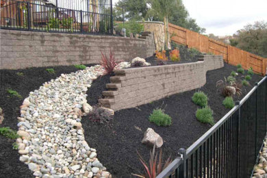 This is an example of a large traditional sloped full sun formal garden for winter in Sacramento with a retaining wall and mulch.