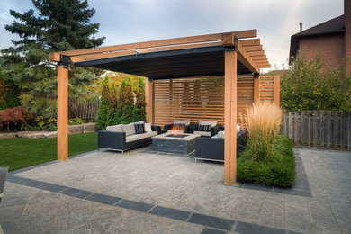 Immagine di un patio o portico minimalista dietro casa con un focolare e una pergola