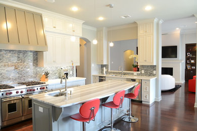 Example of a mid-sized trendy u-shaped medium tone wood floor open concept kitchen design in Austin with an undermount sink, white cabinets, granite countertops, gray backsplash, mosaic tile backsplash, stainless steel appliances and two islands