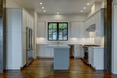 Mid-sized mountain style u-shaped medium tone wood floor and brown floor kitchen photo in Other with an undermount sink, shaker cabinets, white cabinets, quartz countertops, white backsplash, wood backsplash, stainless steel appliances and an island