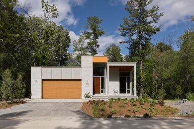 This is an example of a mid-sized contemporary split-level grey house exterior in Ottawa with mixed siding and a flat roof.