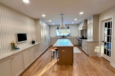 Inspiration for a large transitional u-shaped light wood floor and brown floor eat-in kitchen remodel in Chicago with an undermount sink, flat-panel cabinets, beige cabinets, quartzite countertops, beige backsplash, quartz backsplash, paneled appliances, an island and beige countertops