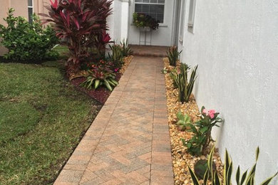 This is an example of a mid-sized full sun front yard brick garden path in Miami.