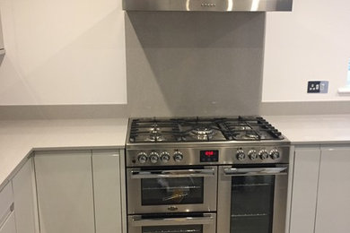 Example of a large minimalist l-shaped vinyl floor and gray floor eat-in kitchen design in Other with a drop-in sink, flat-panel cabinets, gray cabinets, quartzite countertops, gray backsplash, stainless steel appliances and no island