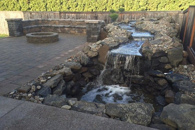 Photo of a traditional concrete paver landscaping in Portland with a fire pit.