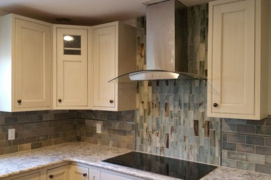 Enclosed kitchen - mid-sized traditional l-shaped enclosed kitchen idea in Baltimore with shaker cabinets, white cabinets, granite countertops, gray backsplash, stone tile backsplash, stainless steel appliances and an island