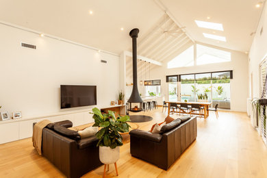 This is an example of a scandinavian living room with light hardwood floors and a hanging fireplace.