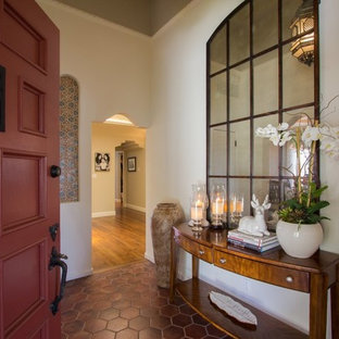 ロサンゼルスの中サイズの片開きドア地中海スタイルのおしゃれな玄関ロビー (ベージュの壁、テラコッタタイルの床、赤いドア、赤い床) の写真