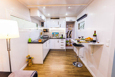 Foto de cocinas en L minimalista de tamaño medio abierta con fregadero de un seno, armarios con paneles lisos, puertas de armario blancas, suelo de madera en tonos medios y península