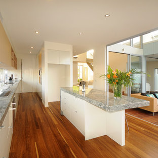 Mid-sized beach style kitchen pantry pictures - Kitchen pantry - mid-sized beach style galley medium tone wood floor kitchen pantry idea in Sunshine Coast with an undermount sink, white cabinets, marble countertops, glass sheet backsplash, stainless steel appliances and an island