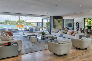 Example of a minimalist formal and open concept light wood floor and brown floor living room design in Miami with white walls