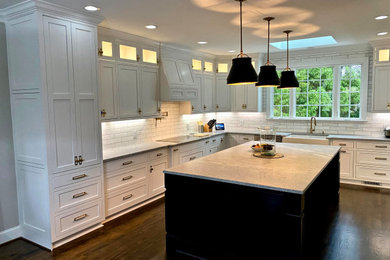 Large eclectic l-shaped eat-in kitchen in Raleigh with a farmhouse sink, shaker cabinets, white cabinets, granite benchtops, white splashback, marble splashback, stainless steel appliances, dark hardwood floors, with island, brown floor and grey benchtop.