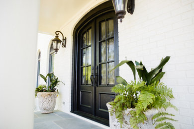 Example of a large classic brick wall entryway design in Charlotte with white walls and a black front door