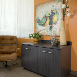 This is an example of a medium sized modern study in Orange County with orange walls, bamboo flooring and a built-in desk.