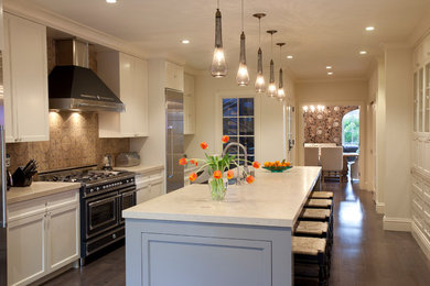 Example of a large trendy l-shaped dark wood floor and brown floor eat-in kitchen design in San Francisco with white cabinets, granite countertops, beige backsplash, an island, a farmhouse sink, shaker cabinets and stainless steel appliances