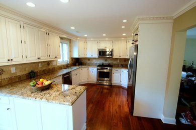 Inspiration for a mid-sized l-shaped medium tone wood floor open concept kitchen remodel in New York with an integrated sink, raised-panel cabinets, white cabinets, granite countertops, brown backsplash, mosaic tile backsplash and stainless steel appliances