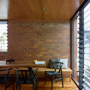 Photo of a mid-sized midcentury open plan dining in Brisbane with white walls, light hardwood floors, brown floor, timber and brick walls.
