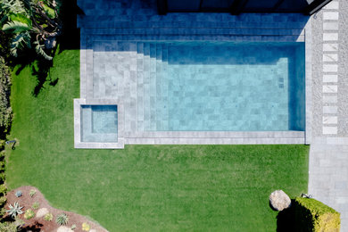 Example of a backyard tile and rectangular pool design in Other