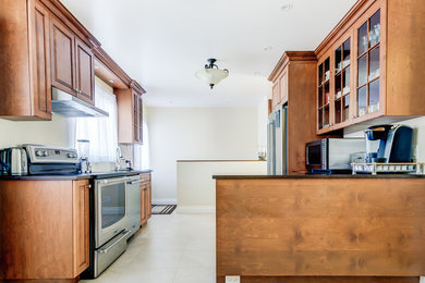 Inspiration for a mid-sized transitional l-shaped porcelain tile eat-in kitchen remodel in Montreal with an undermount sink, raised-panel cabinets, dark wood cabinets, stainless steel appliances, an island and quartzite countertops