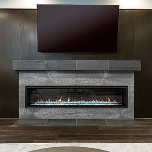Photo of a medium sized contemporary look-out basement in DC Metro with grey walls, dark hardwood flooring, a ribbon fireplace, a concrete fireplace surround and brown floors.