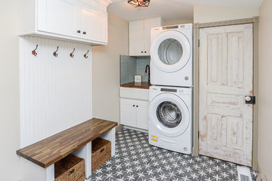 Example of a mid-sized country single-wall utility room design in Philadelphia with an undermount sink, beige walls and a stacked washer/dryer