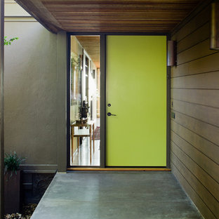 Выдающиеся фото от архитекторов и дизайнеров интерьера: большая входная дверь в стиле ретро с коричневыми стенами, бетонным полом, одностворчатой входной дверью и зеленой входной дверью