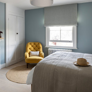 Mittelgroßes Klassisches Gästezimmer mit blauer Wandfarbe, hellem Holzboden, Kamin, verputzter Kaminumrandung und beigem Boden in London