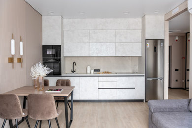 Contemporary single-wall eat-in kitchen in Other with a single-bowl sink, flat-panel cabinets, porcelain splashback, black appliances, vinyl floors and beige benchtop.