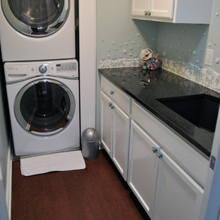 カンザスシティの中サイズのトラディショナルスタイルのおしゃれな洗濯室 (シングルシンク、落し込みパネル扉のキャビネット、白いキャビネット、御影石カウンター、青い壁、コルクフローリング、上下配置の洗濯機・乾燥機) の写真