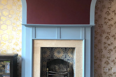 Inspiration for a small bohemian formal enclosed living room in London with red walls, carpet, a standard fireplace, a wooden fireplace surround, a freestanding tv, grey floors and wallpapered walls.