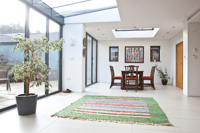 Expansive modern open plan dining room in Cardiff with white walls, porcelain flooring, no fireplace and white floors.