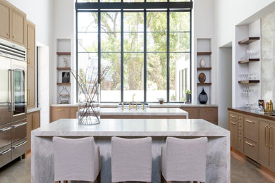Example of a huge trendy u-shaped medium tone wood floor, brown floor and exposed beam open concept kitchen design in Dallas with a farmhouse sink, beaded inset cabinets, medium tone wood cabinets, marble countertops, marble backsplash, stainless steel appliances, two islands, beige backsplash and beige countertops