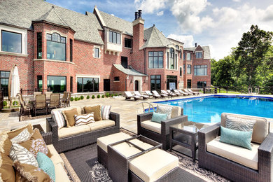 Example of a huge classic red three-story brick gable roof design in Other