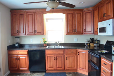 Mid-sized trendy l-shaped linoleum floor eat-in kitchen photo in Philadelphia with a drop-in sink, raised-panel cabinets, medium tone wood cabinets, wood countertops, black backsplash, black appliances and no island